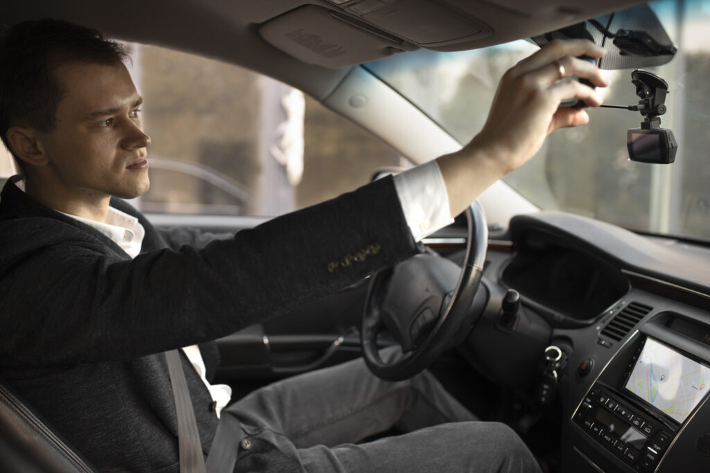 Man Driving While Adjusting Dashcam 1024x683